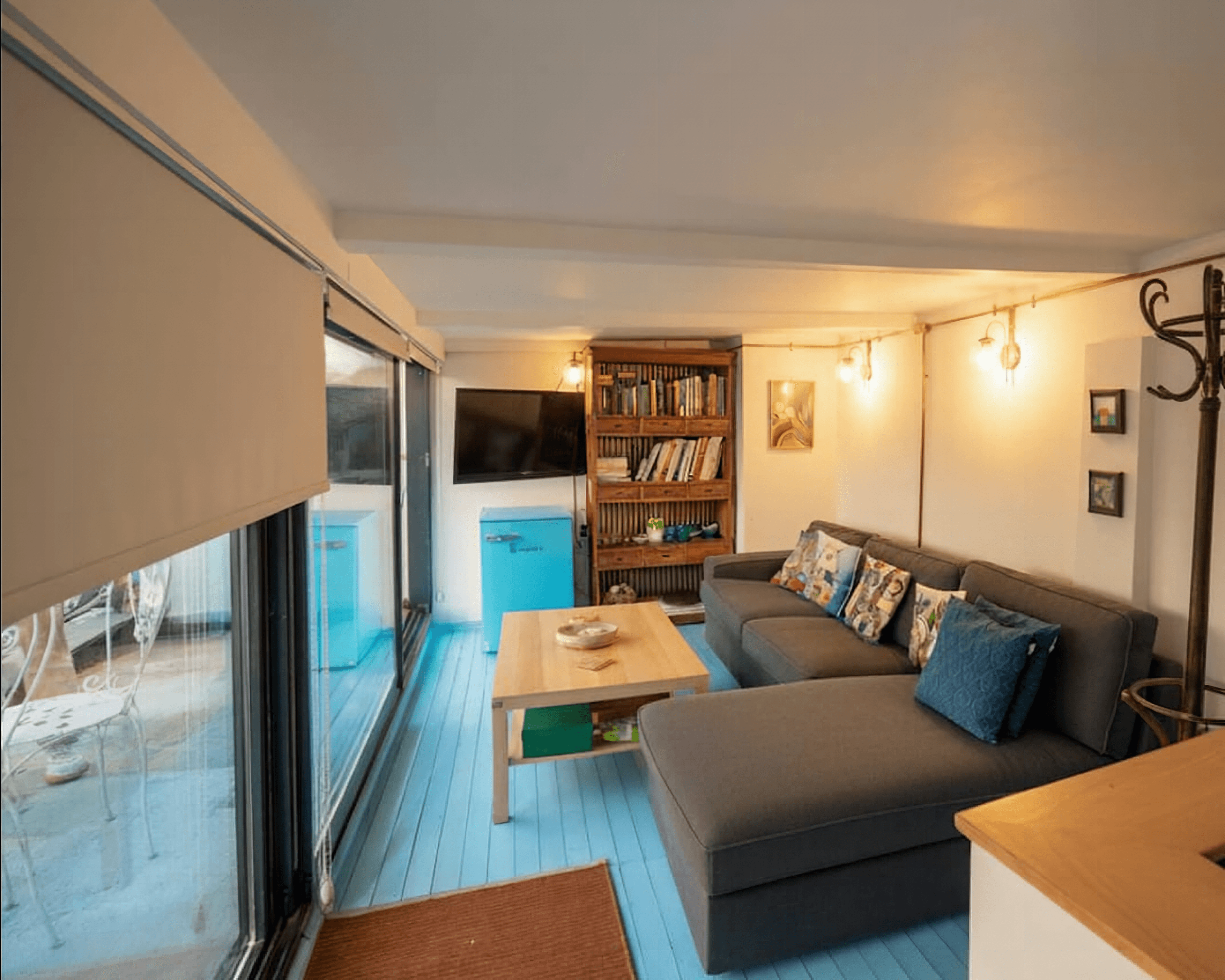 Cozy living room with gray sofa, blue floors, and Edison string lights